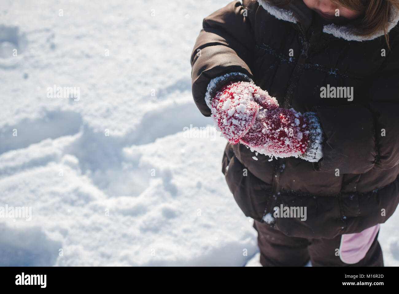 Ein 3-jähriges Kind tragen Winterkleidung, winter Fäustlinge, spielt im Schnee an einem sonnigen Wintertag in den Vereinigten Staaten. Stockfoto