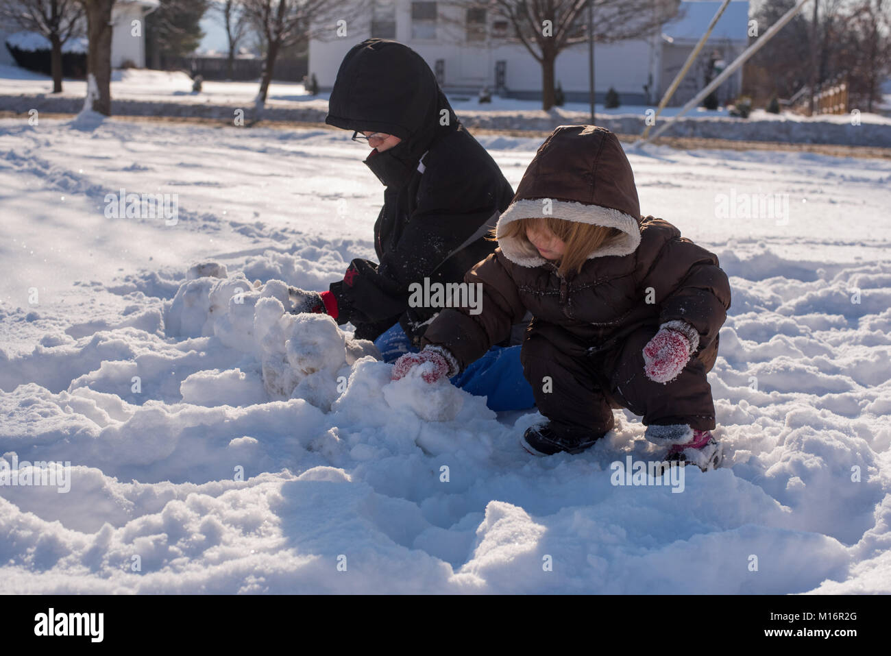 Zwei Kinder tragen Winter Kleidung spielen im Schnee an einem sonnigen Tag in den Vereinigten Staaten. Stockfoto