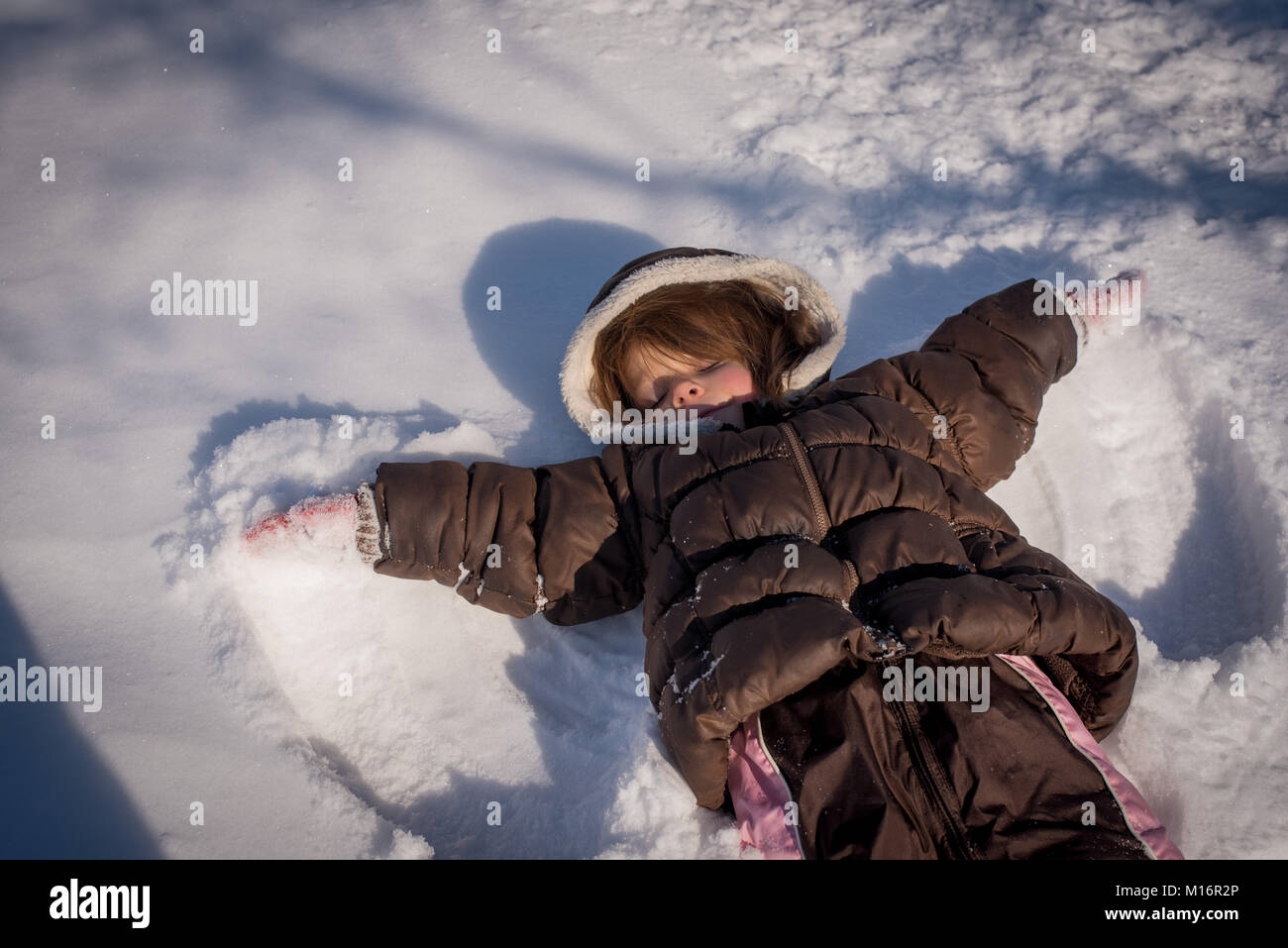 Ein 3-jähriges Mädchen macht einen Schnee Engel im Schnee im Nordosten der Vereinigten Staaten von Amerika. Stockfoto