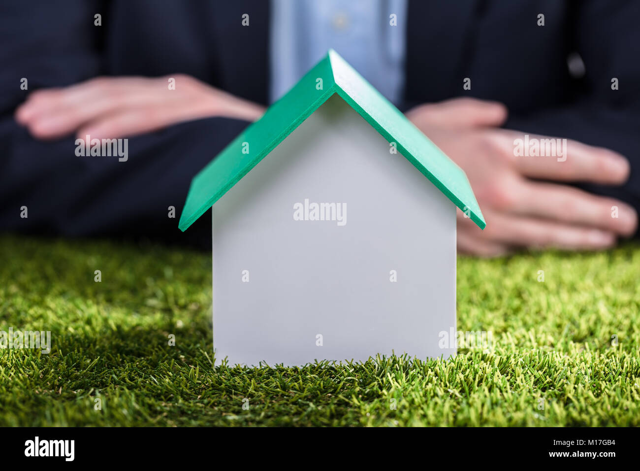 Nahaufnahme eines Hauses Modell auf grünem Gras Vor dem Geschäftsmann, Hand Stockfoto