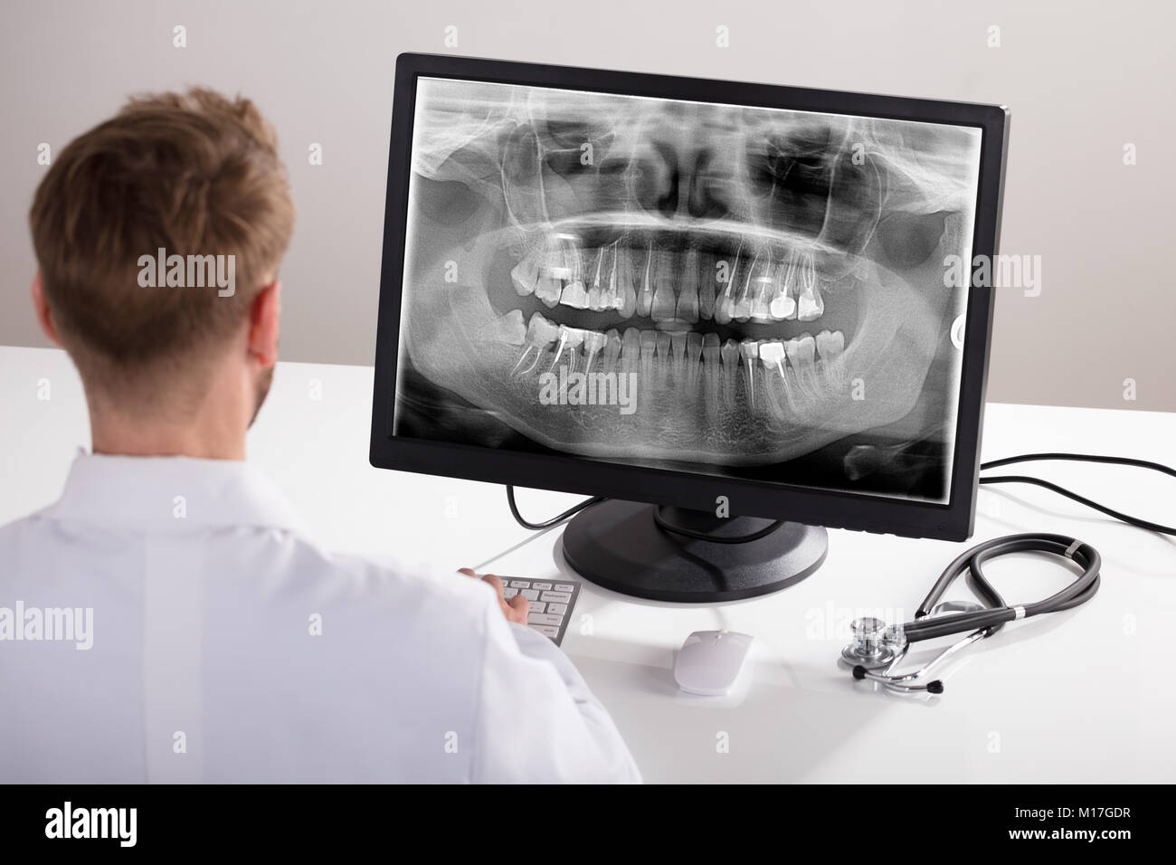 Rückansicht eines männlichen Arzt Suchen an X-ray auf dem Computer Stockfoto