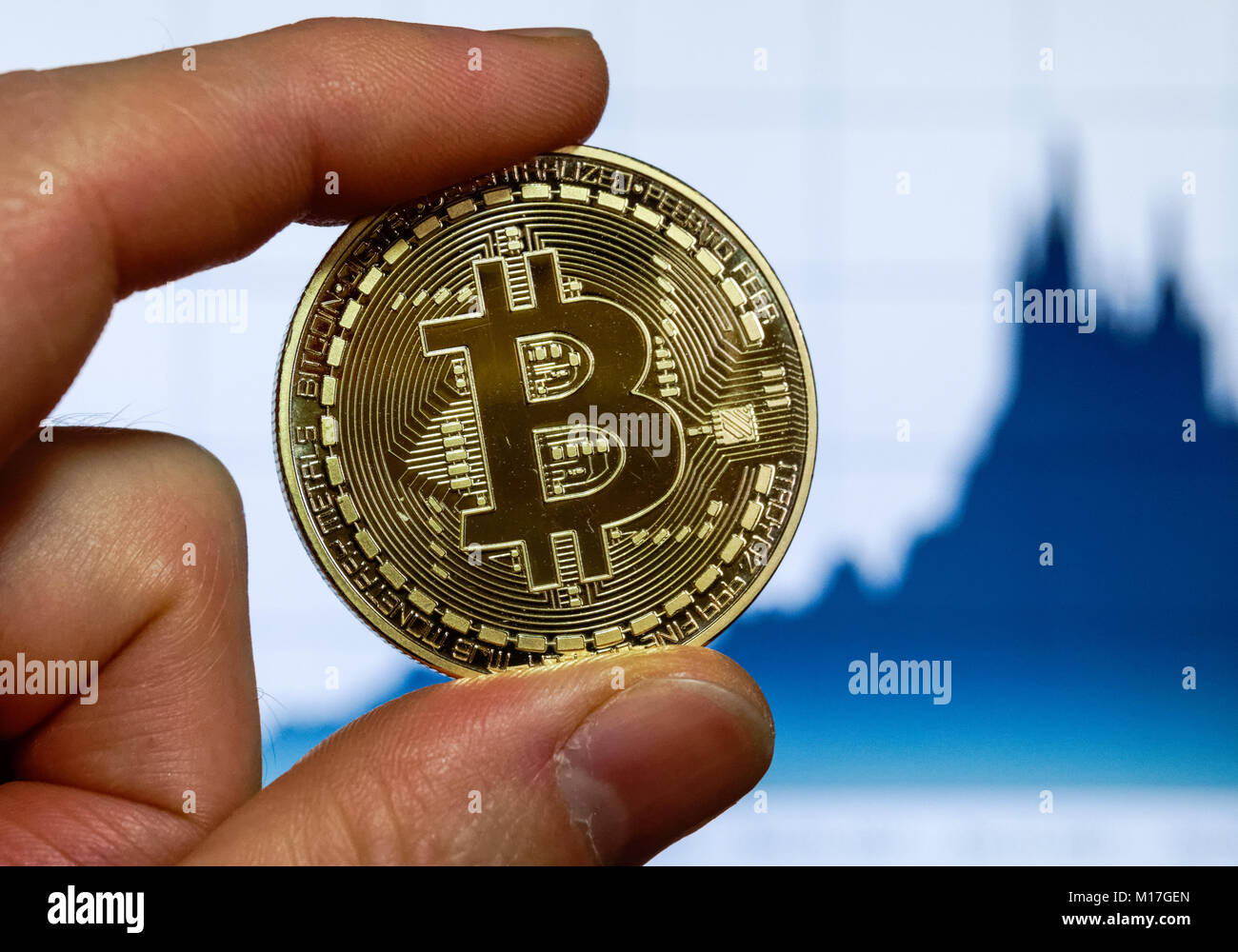 Bitcoin cryptocurrency Münze vor einem Computer Bildschirm mit bitcoin Chart Stockfoto