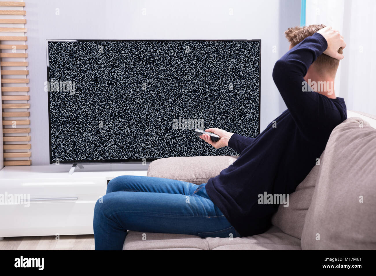 Mann sitzt auf einem Sofa, Fernseher mit Kein Signal Stockfoto