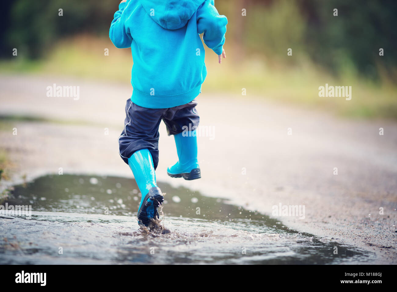 Kind zu Fuß in Gummistiefel in Pfütze auf Regenwetter Stockfoto
