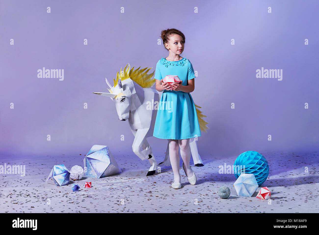 Hübsches Mädchen in einem eleganten blauen Kleid für Mädchen im Teenageralter mit einem Make-up. Origami und Minimalismus. Fashion Kid. Romantisches kleines Mädchen. Stockfoto