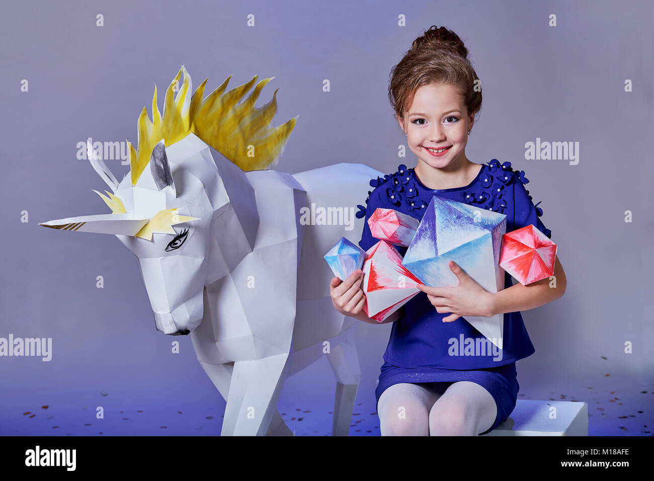 Mode Kind lächelnd. Charmante Kinder Mädchen im Studio hält eine origami Figur. Stockfoto