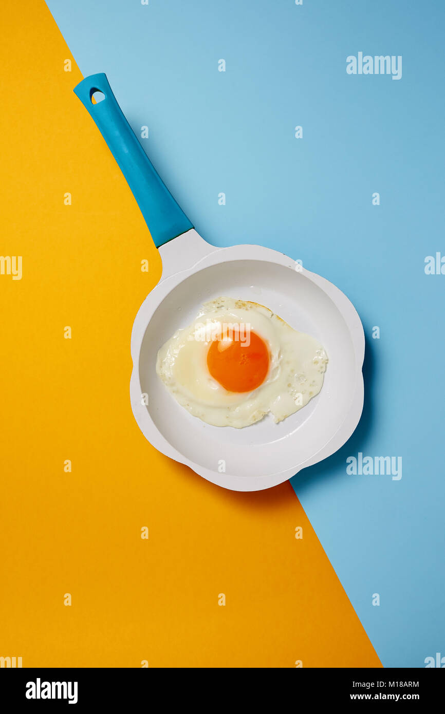 Spiegelei in der Pfanne auf farbigem Hintergrund Stockfoto