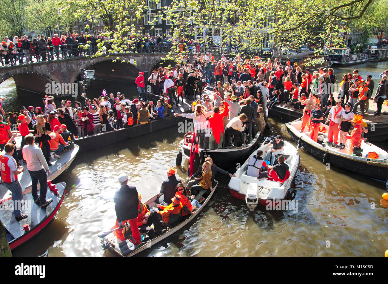 Ein Stau auf Amsterdam Canal auf King's Tag. Mehrere Boote auf einer Kreuzung stecken alle voller glücklich feiern Menschen. Stockfoto