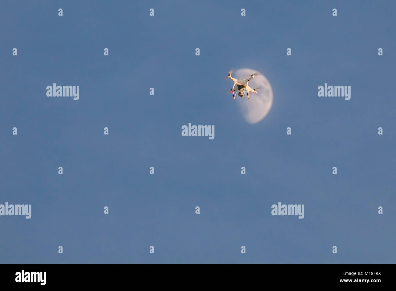 Fliegen weiß drone Phantom auf den blauen Himmel. Landung eines summten Hand mit drehenden Propellern Stockfoto