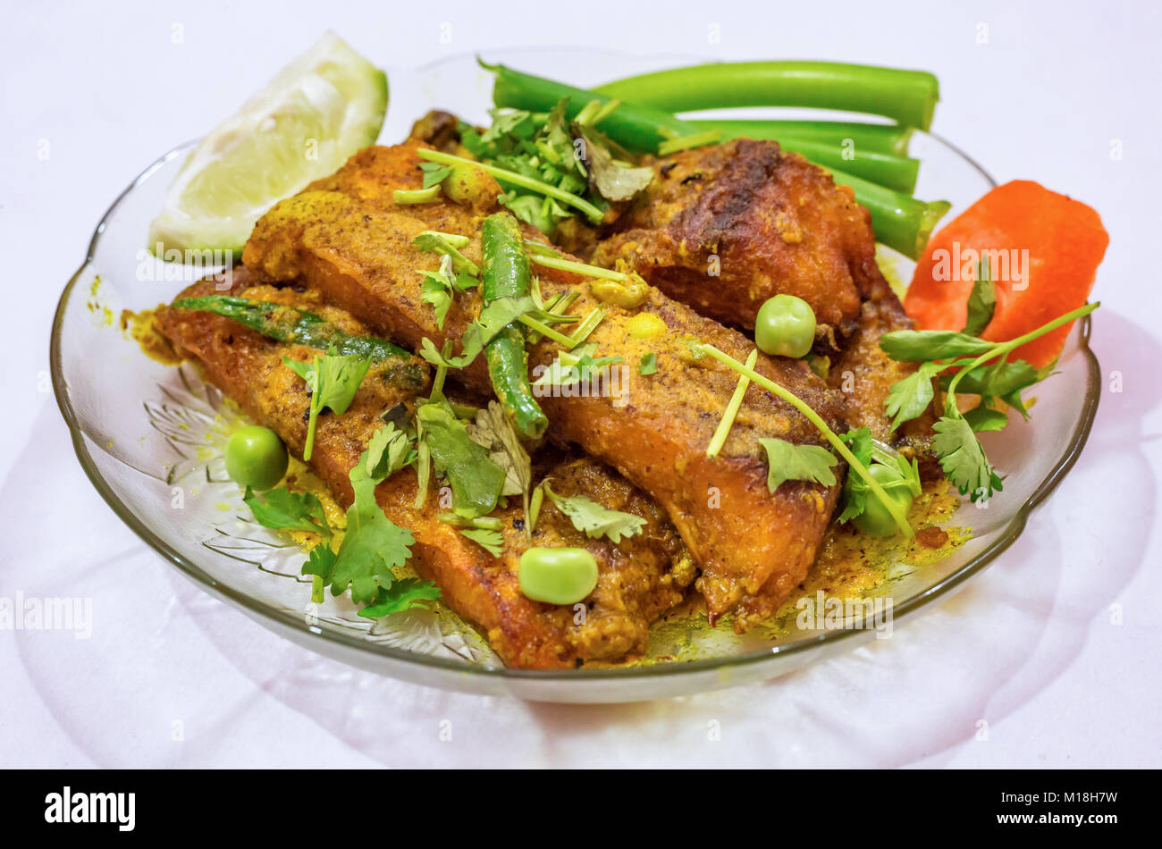 Würzige Rohu Fisch garniert mit Koriander, Bohnen, Karotten, grüne Chilischoten und Zitrone in Scheiben schneiden. Rohu Fisch ist ein beliebter nicht vegetarische Ernährung in Indien. Stockfoto