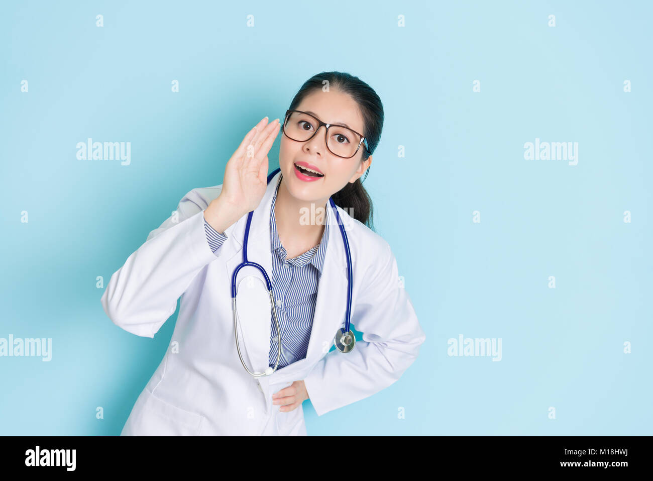 Zuversichtlich Professional Female Arzt Gesicht in die Kamera sprechen, geheime Nachrichten, wenn Sie in der blauen Wand Hintergrund stehen und gute medizinische Informationen Stockfoto