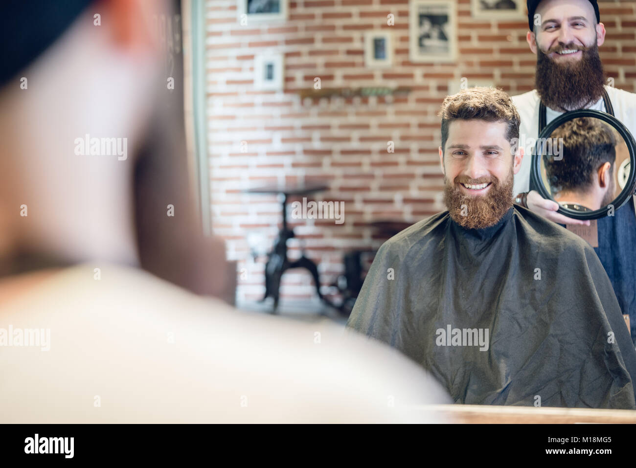 Junger Mann lächelnd, während sie an seiner neuen trendigen Haarschnitt in der Stockfoto