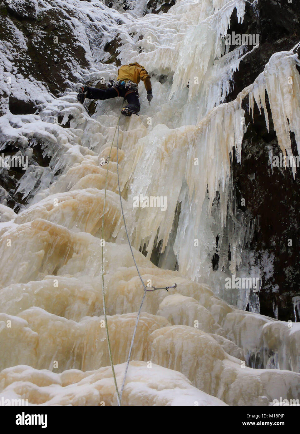 Eiskletterer auf einem steilen gefrorenen Wasserfall im tiefen Winter in den Alpen in der Schweiz Stockfoto