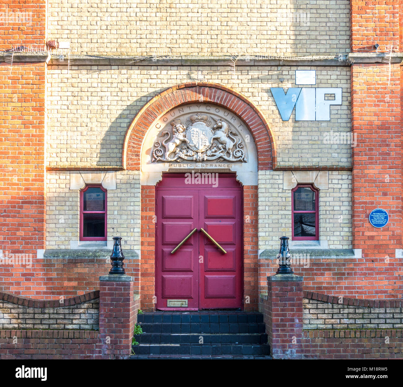 Alte Krone Gericht Doppeltüren Eingang, mit blauen Plakette an der Wand befestigt, in Stadtzentrum von Peterborough, Cambridgeshire, England, UK. Stockfoto