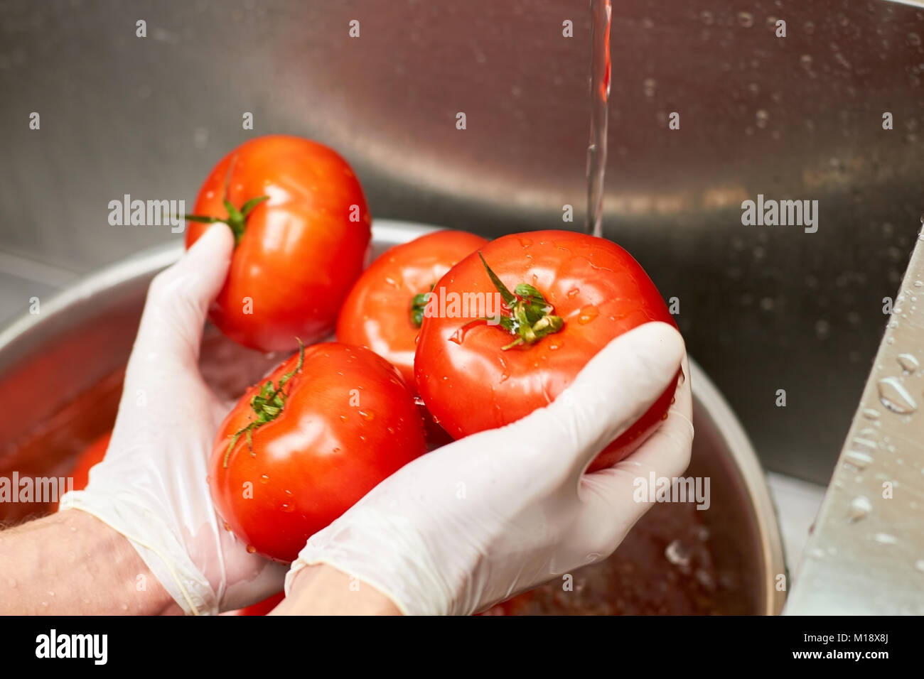 Koch Hände halten nass Tomaten über dem Waschbecken. Stockfoto