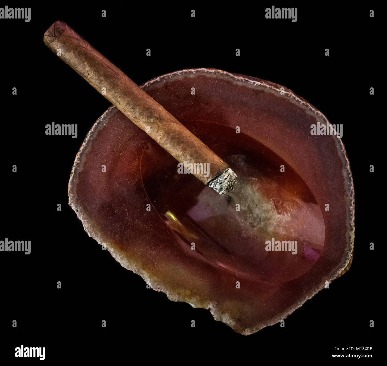Einzelne Leuchten Zigarre auf einem roten Rock Aschenbecher Stockfoto