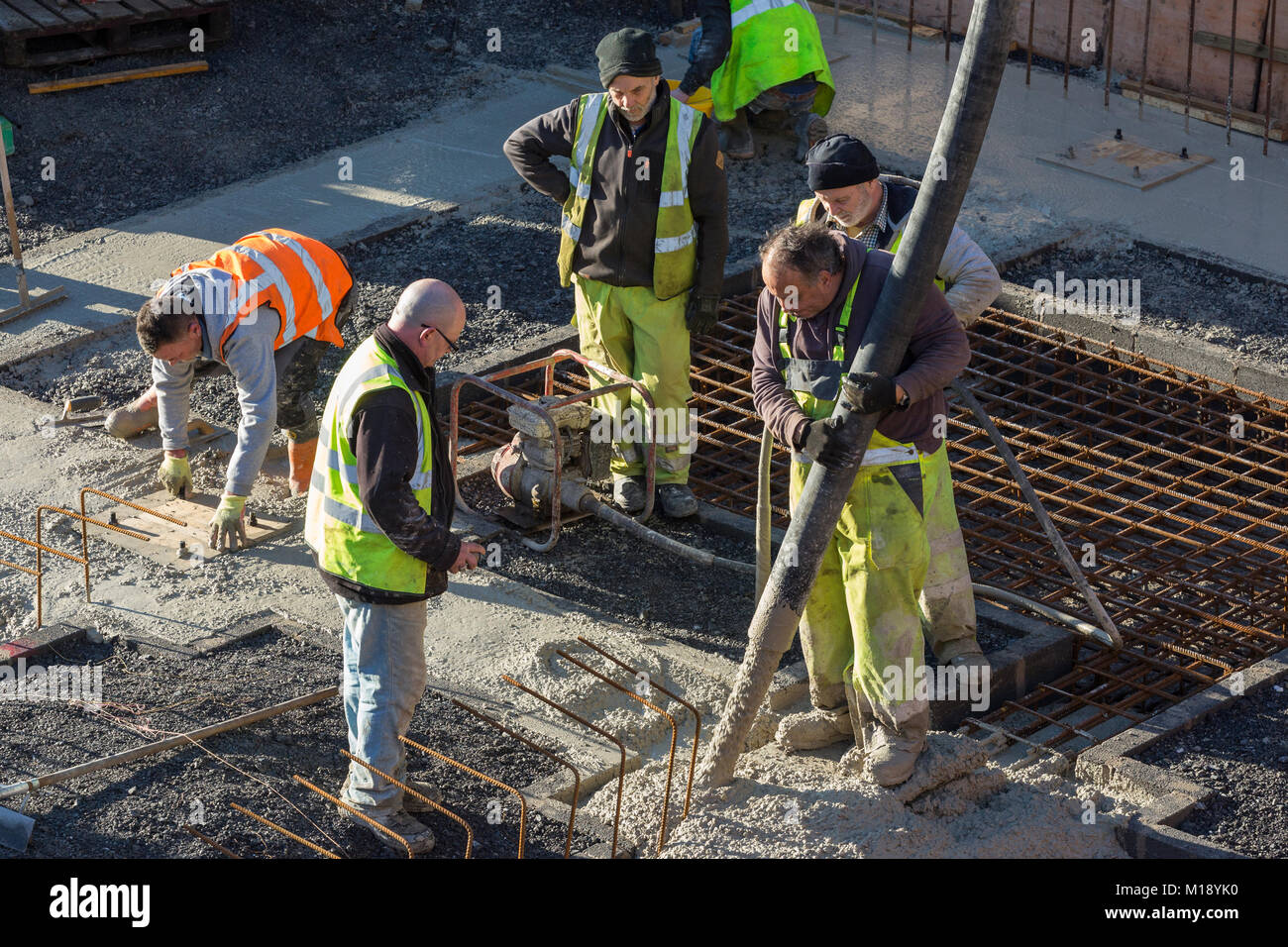 Handwerker in hohe Sichtbarkeit flourescent Jacken auf Gebäude, Beton gießt in Stiftungen Stockfoto