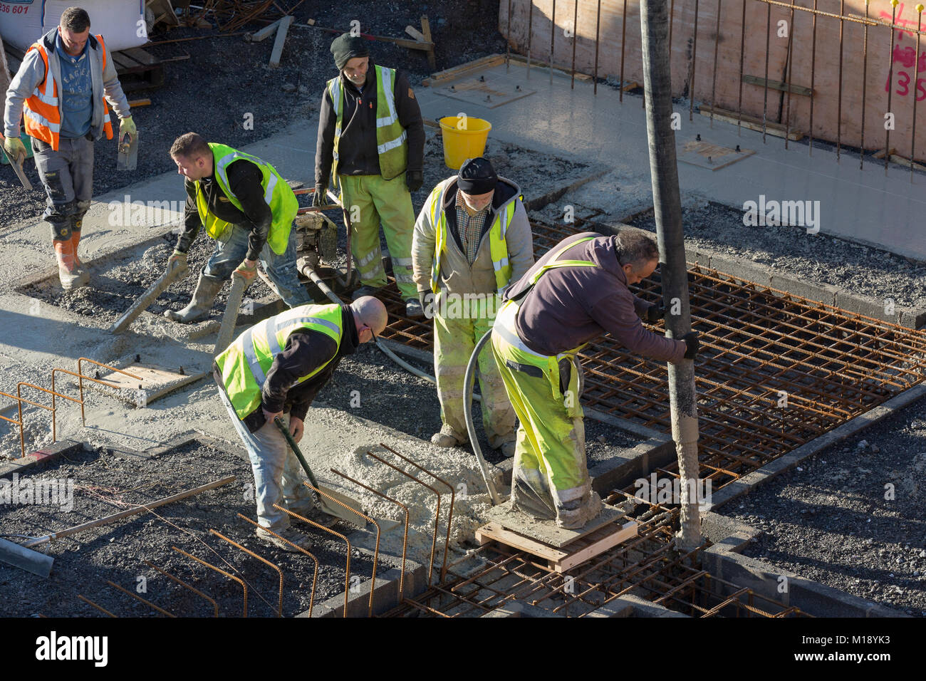 Handwerker in hohe Sichtbarkeit flourescent Jacken auf Gebäude, Beton gießt in Stiftungen Stockfoto