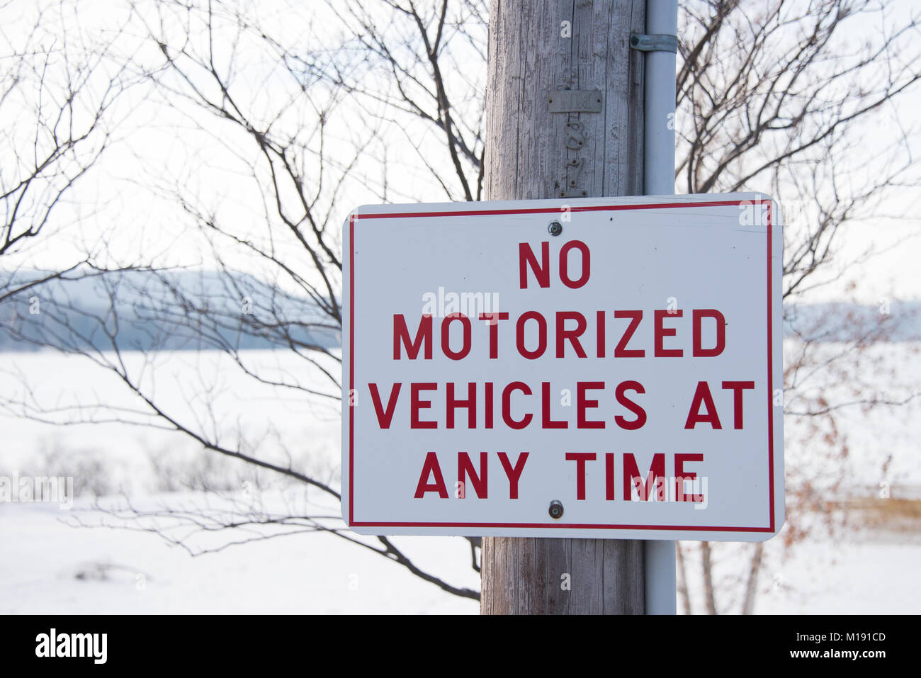 Rote und weiße Zeichen in Parkstellung angibt, keine motorisierten Fahrzeuge jederzeit in der Spekulant, NY USA im Winter, mit Schnee und gefrorenen See im Hintergrund. Stockfoto