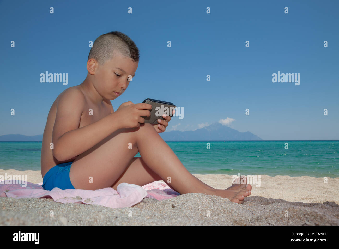 Jungen spielen Smartphone Strand Stockfoto