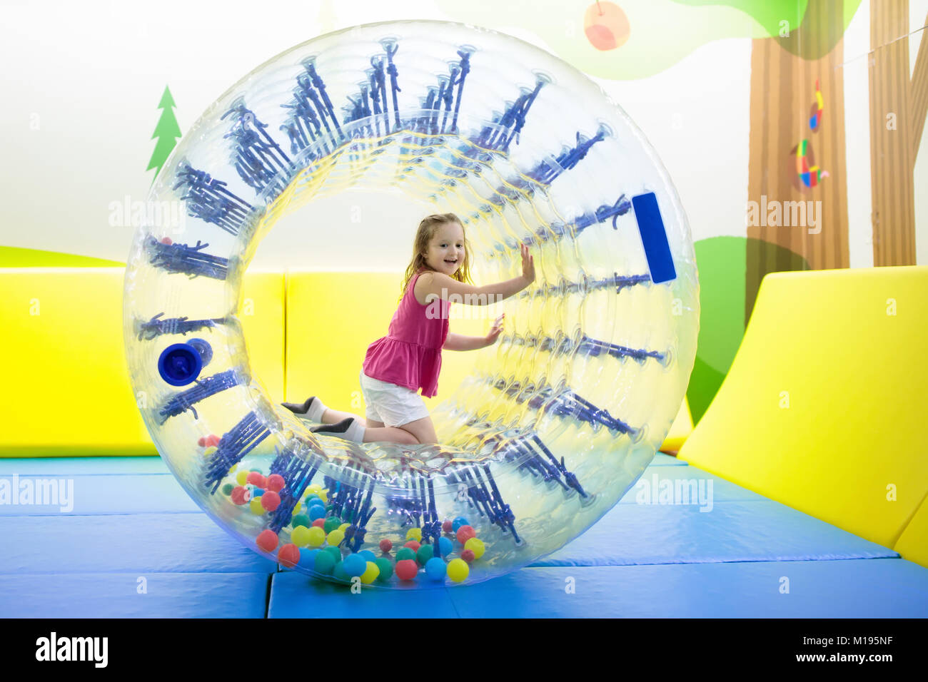 Kind im Laufrad springen auf bunten Spielplatz Trampolin. Kinder springen in Aufblasbare bounce Burg auf Kindergarten Geburtstag. Aktivität und pl Stockfoto