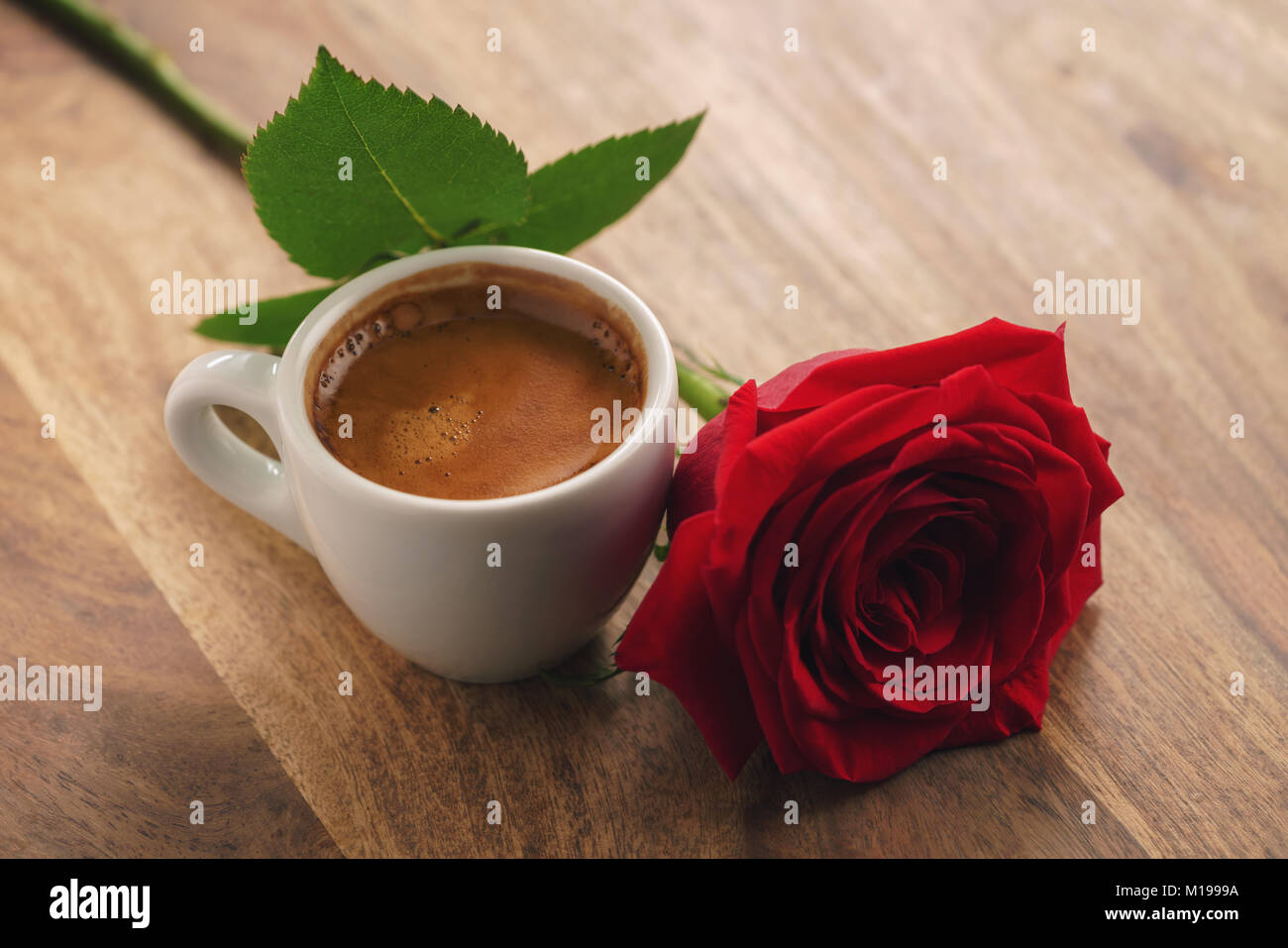 Frischen Espresso mit roter Rose Blume auf Holz Tisch Stockfoto