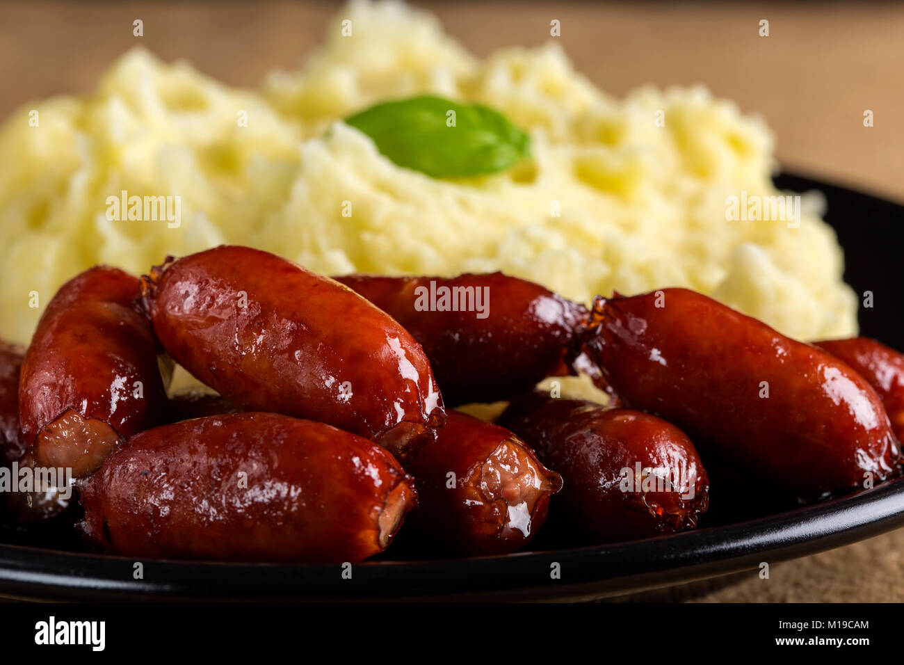 Nahaufnahme von Würstchen auf Platte mit Kartoffelpüree im Hintergrund Stockfoto