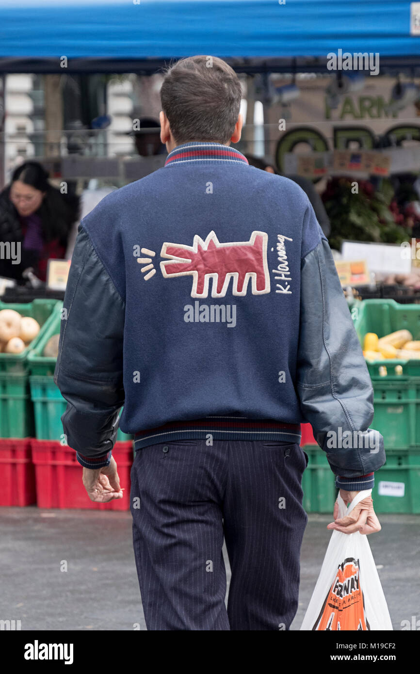 Ein Mann, der eine Jacke mit Keith Haring Kunst auf der Rückseite. Im Union Square grünen Markt in Lower Manhattan, New York City. Stockfoto