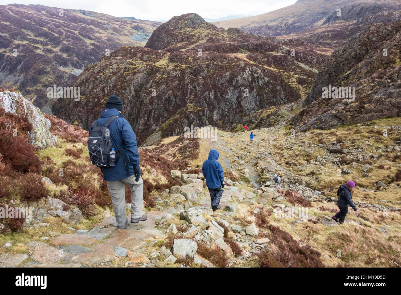 Wanderer in absteigender Reihenfolge von Heuballen auf dem Weg zwischen grünen Felsen und große Runde Wie in Richtung Honister, Lake District, Cumbria, England, Großbritannien Stockfoto