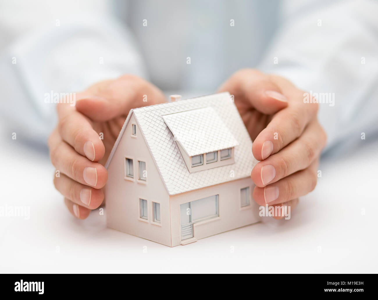 Sachversicherung. Haus Miniatur von Händen bedeckt. Stockfoto