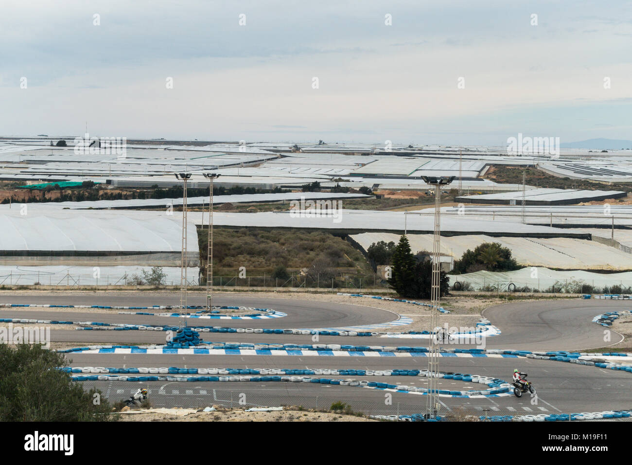 Invernaderos, Gewächshäuser, Treibhäuser für Boden freien Kulturen mit Motorrad Race Track im Vordergrund in Murcia, Spanien Stockfoto