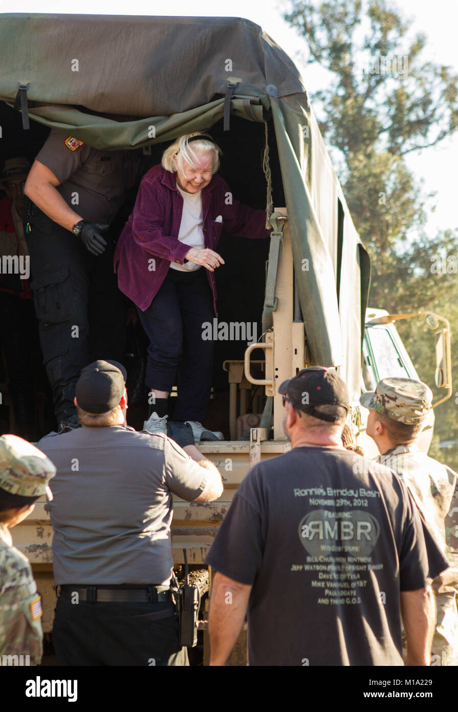 Sanitäter und Soldaten aus der 1114Th Kalifornien Nationalgarde Composite Transport Unternehmen helfen, eine 90-jährige Frau steigen aus einem Light Medium tactical Vehicle (LMTV) nach der Evakuierung der Frau von ihrem Montecito, Kalifornien, Nachbarschaft zu einer zentralisierten Drop-off Punkt in der Stadt, Jan. 11, 2018. Tiefen Schlamm auf Stadt Straßen verlassen hat, einige Stadtteile von Critical Services und Bewohner, die in Ort während eines Sturms früh in der Woche geschnitten werden müssen, ihre Häuser zu verlassen. Cal Guard LMTVs sind Hoch wasser Fahrzeuge, die mit der Fähigkeit zu reisen Fahrbahnen für die meisten Unpassierbar ca Stockfoto