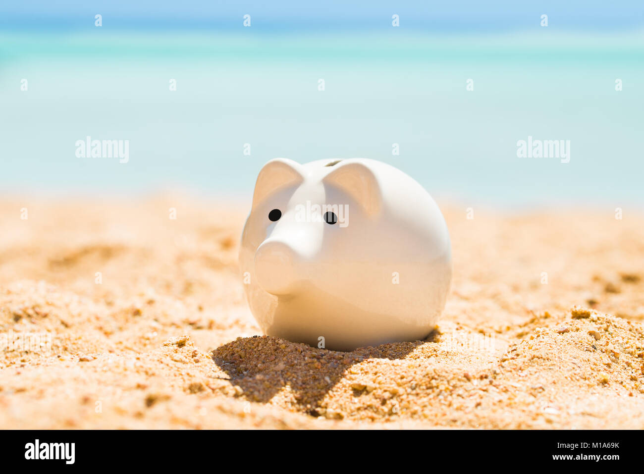 Eine weiße Sparschwein auf Sand am Strand im Sommer Stockfoto