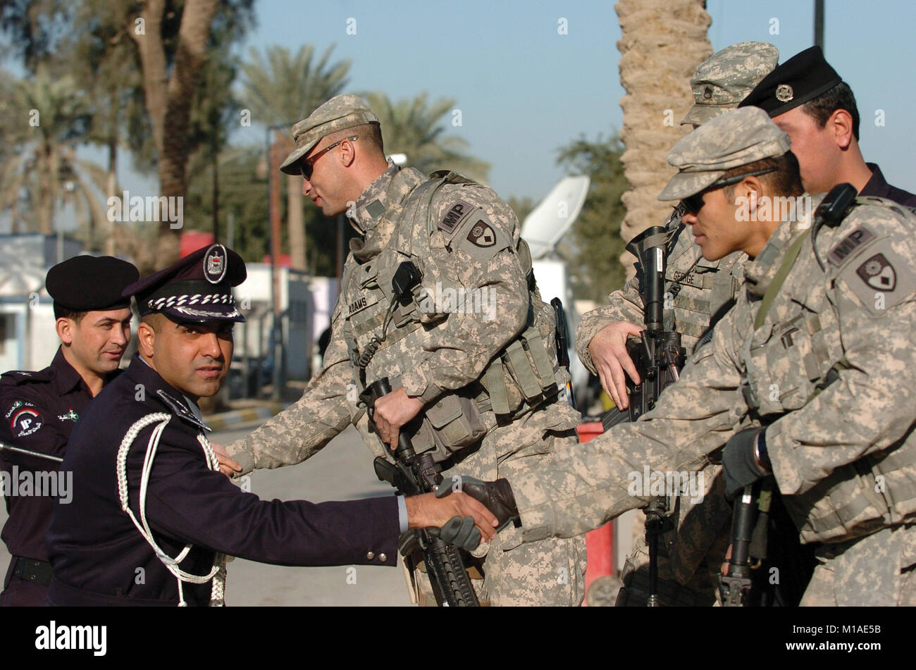 100312-A-001 -0691 S Soldaten der 49th Military Police Brigade (SPC. Wesley Adams, Links, SPC. Rommel Vazquez, rechts, und Staff Sgt. Keith George, versteckte) Grüße irakische Polizisten. Die Soldaten sind Mitglieder der 49 th Personal Security Detail, die eine wichtige Rolle für die Kalifornien Brigade während des Nationalen irakischen Wahlen März 7 gespielt. (Army National Guard Foto/SPC. Eddie Siguenza) Stockfoto