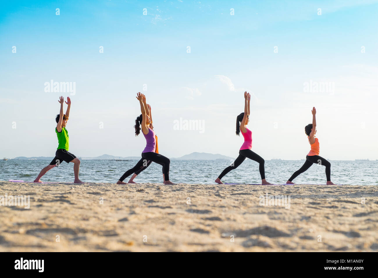 Yoga am Meer Strand im Sonnenuntergang, Gruppe von Menschen tun Krieger wirft mit Clam emotion am Strand entspannen, Meditation, Wellness und gesunden Bala Stockfoto