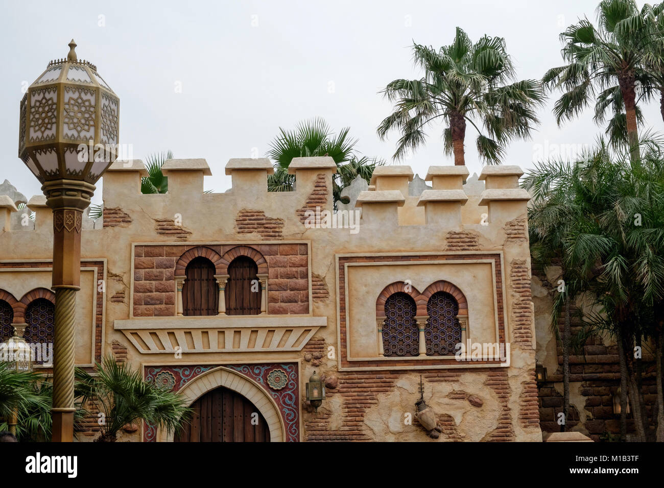 Arabische Architektur mit Straßenlaterne im Vordergrund und Gebäude mit arabischem Design Windows. Palmen im Hintergrund. Arabische Küste, Disneysea Tokio. Stockfoto