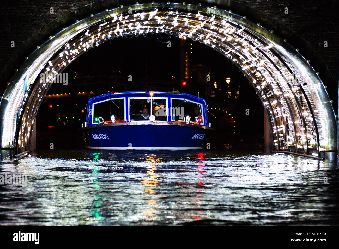 Ein Kanal Lastkahn geht unter einem Tunnel mit Beleuchtung für das jährliche Festival des Lichts in Amsterdam, Niederlande. Stockfoto