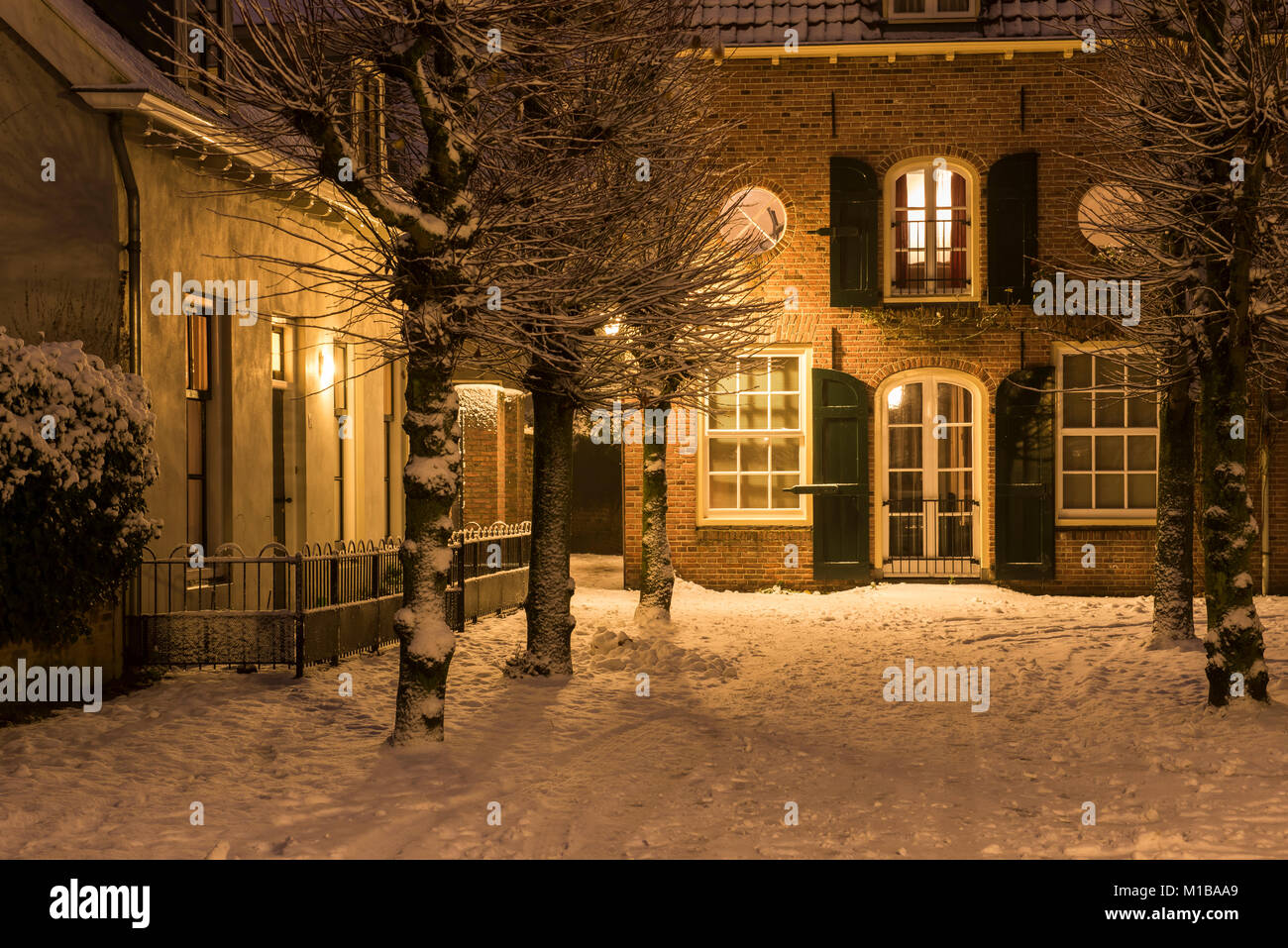 Mazijk Straße im Dezember während Weihnachten und Winter Blizzard mit Häusern, Laternen und Schnee in Wijk bij Duurstede, Utrecht. Stockfoto