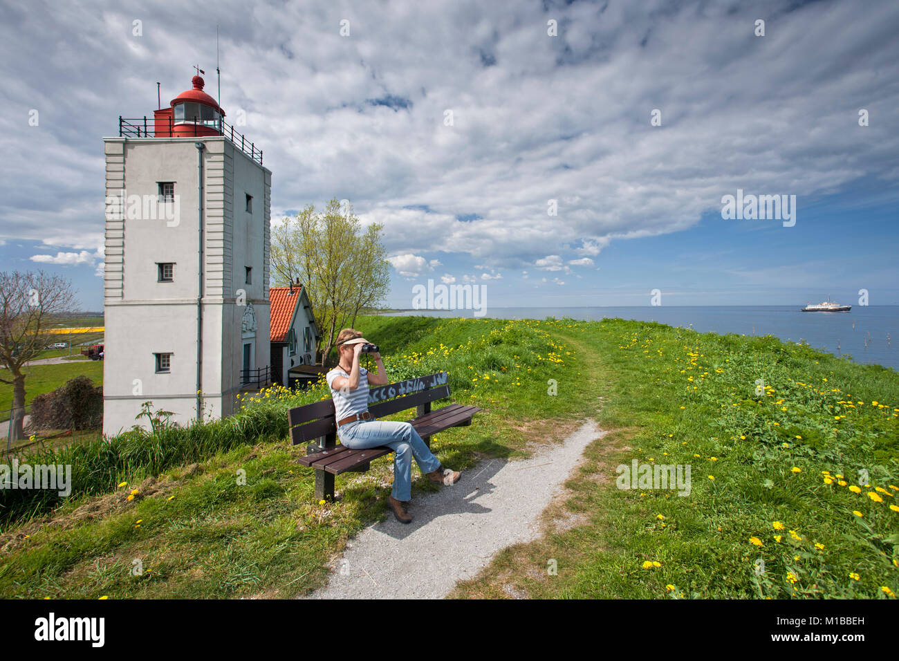 Die Niederlande, Olderhörn genannt, Frau auf der Bank in der Nähe von ehemaligen Leuchtturm am See namens IJsselmeer. Stockfoto