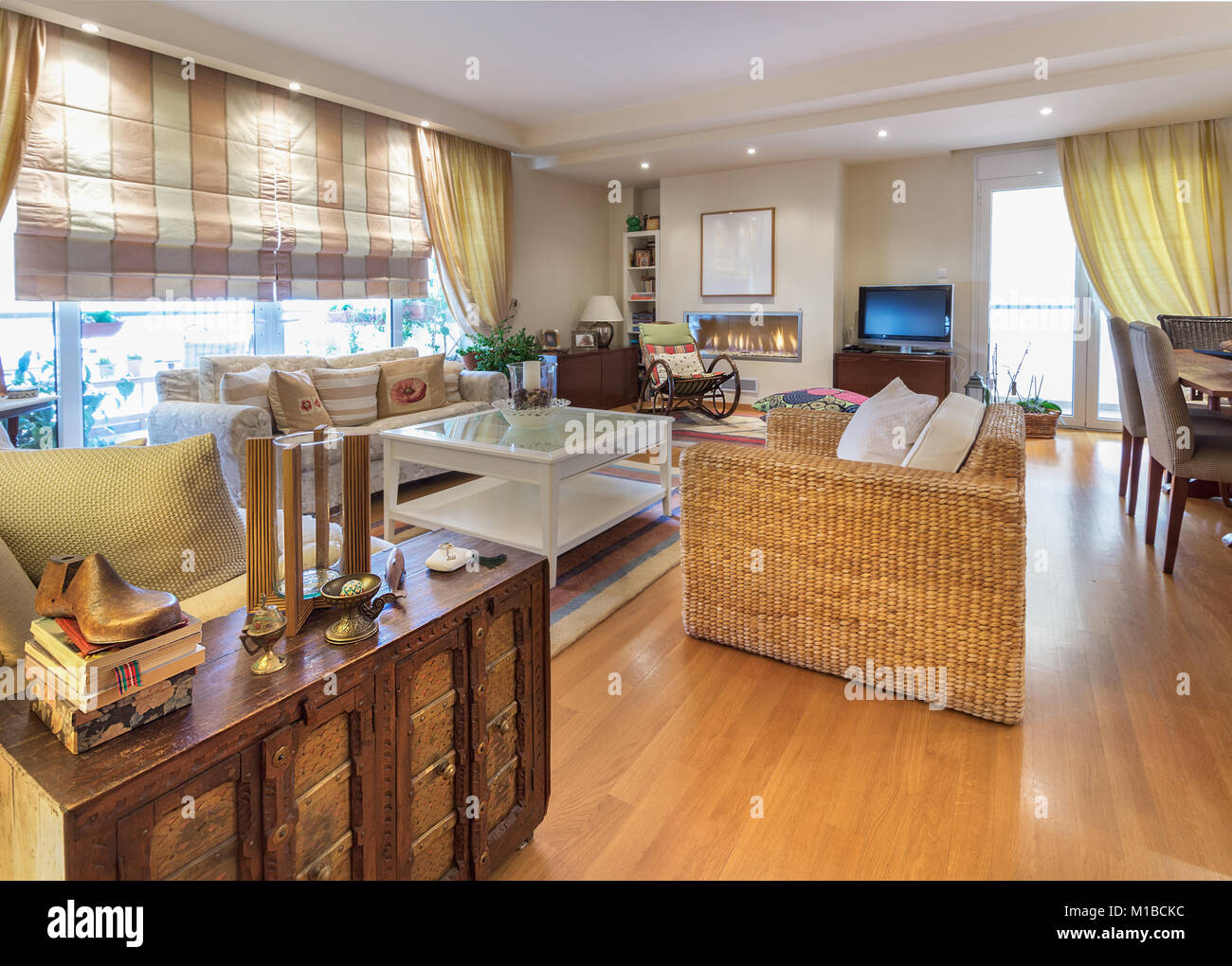 Ein großes Wohnzimmer warmen, zeitgenössischen Stil mit zwei Sofas von zwei doppelsitzer, rockiger bamboo Stuhl, Lampen, Couchtisch und einem Gas Kamin an der Wand Stockfoto
