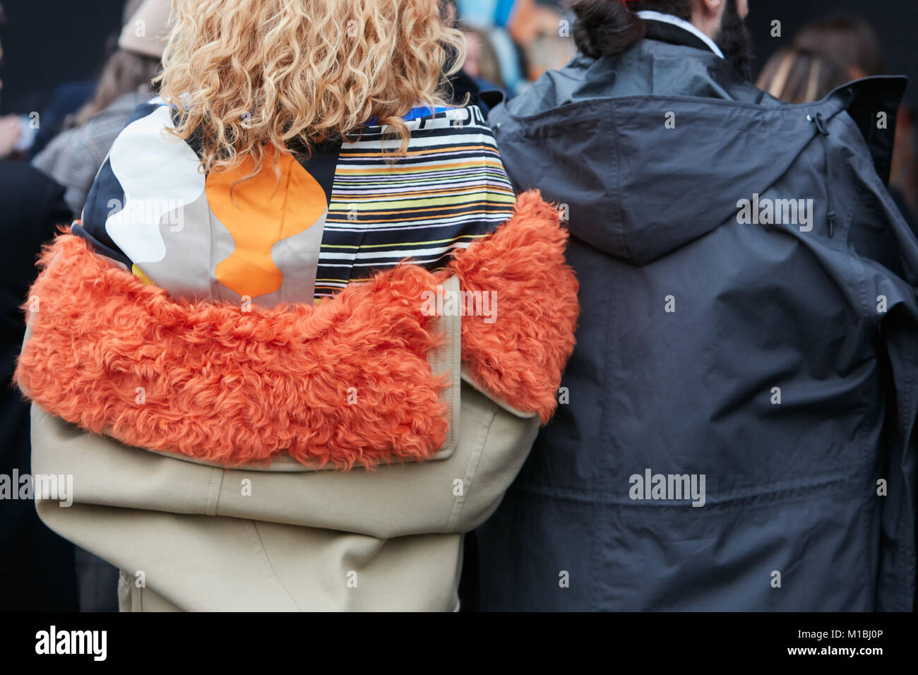 Mailand - Januar 15: Frau mit orange Pelzkragen und Mann mit schwarzen Regenmantel vor Pal Zileri fashion show, Mailand Fashion Week street style April Stockfoto
