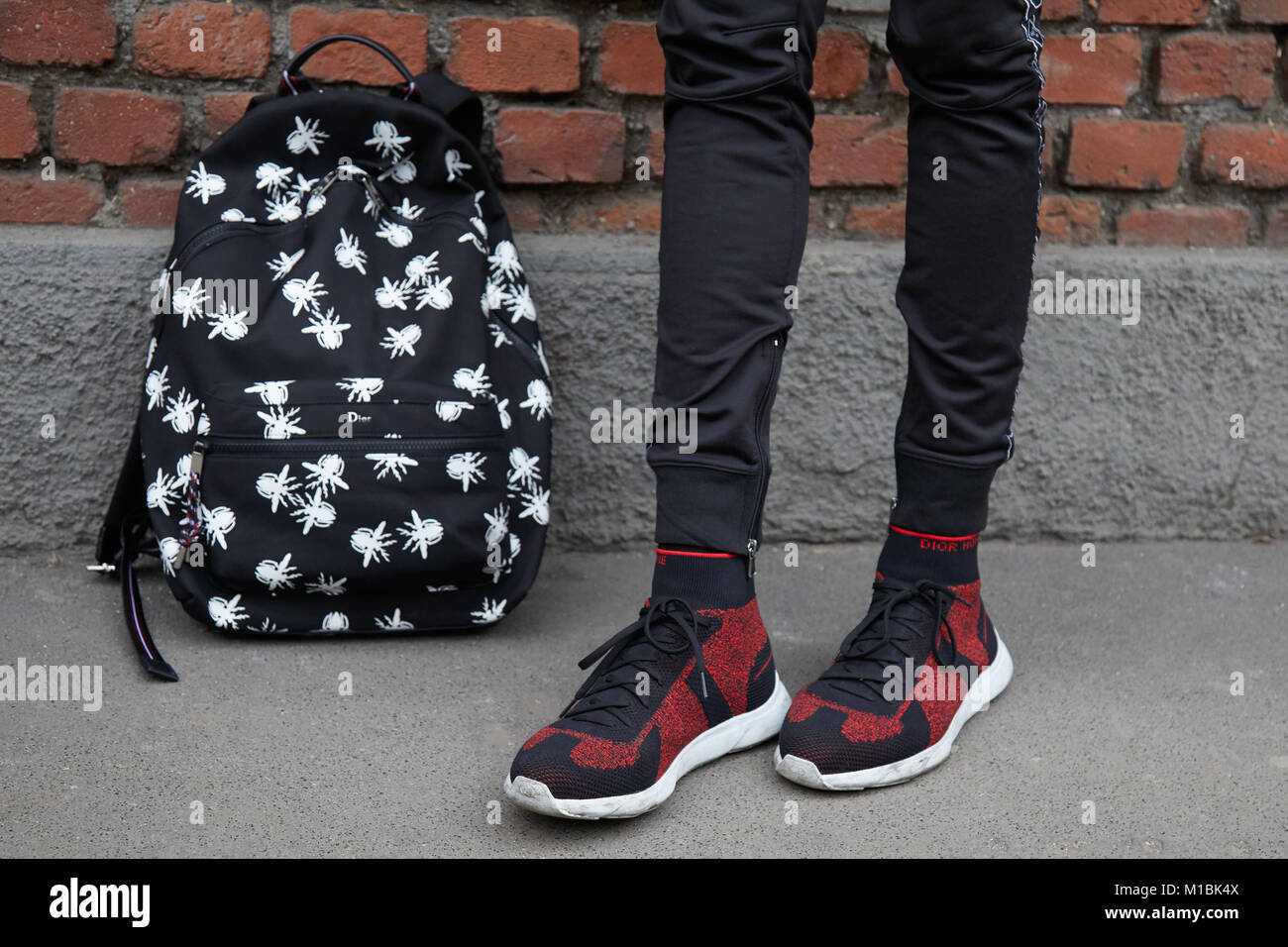 Mailand - Januar 15: Mann mit schwarzen Dior Rucksack mit weißen Mücken und roten und schwarzen Dior Schuhe vor Fendi fashion show, Mailand Fashion Week stree Stockfoto