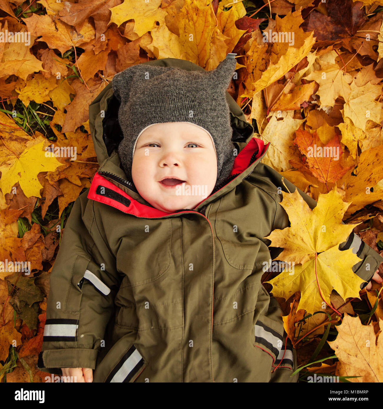 Nettes kleines Baby auf der Blätter im Herbst. Glückliches Kind (6 Monat alt) Stockfoto