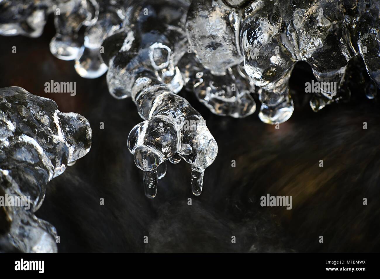 Eiszapfen durch Wasser in einem Bach in Finnland geprägt Stockfoto
