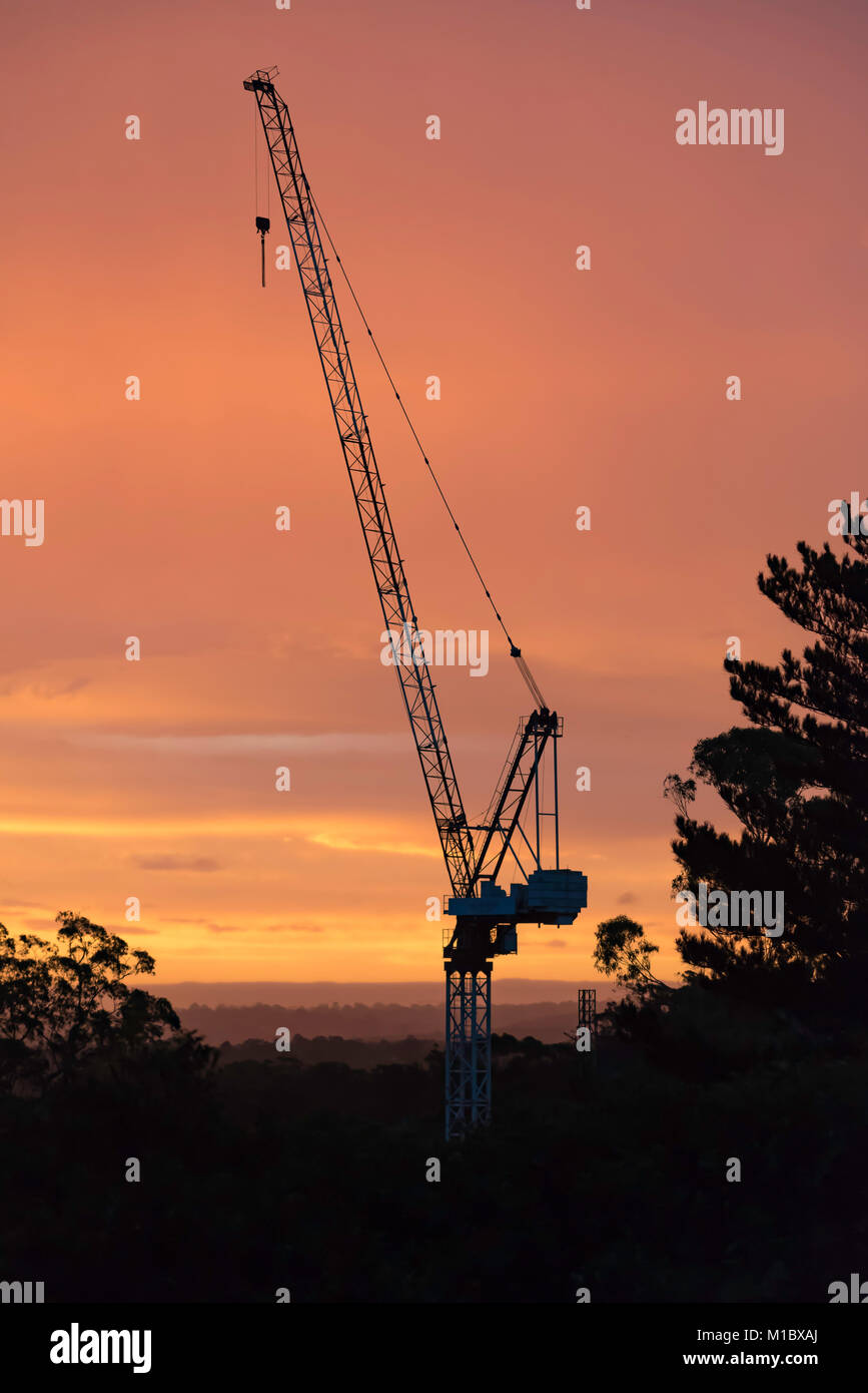 Ein Baukran auf der Baustelle gegen eine orange Sonnenuntergang in Sydney, Australien, Silhouetted Stockfoto