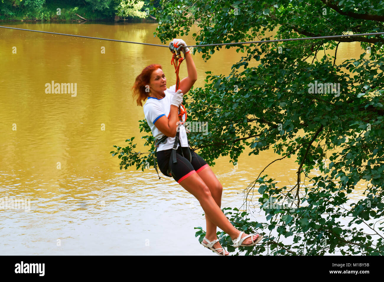 Mädchen in einem Hochseilgarten, Spaß auf den Seilen, fliegende am Seil über den Fluss Stockfoto
