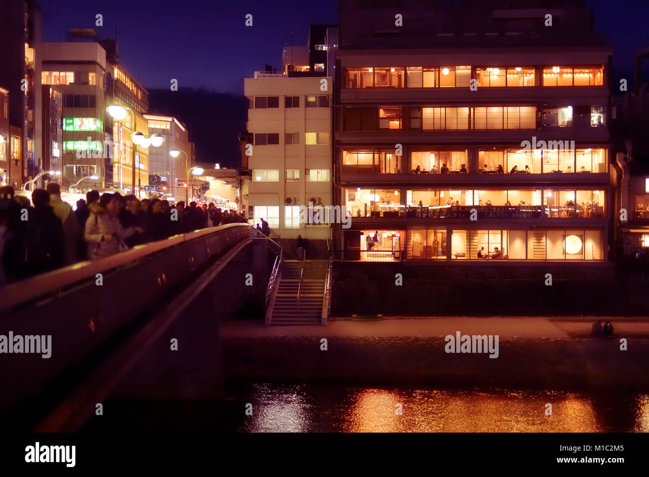 Führerschein verfügbar unter MaximImages.com - Izumoya, japanisches Restaurantgebäude mit nachts beleuchteten Fenstern und Gästen, die drinnen essen. Shijo Brücke rüber Stockfoto