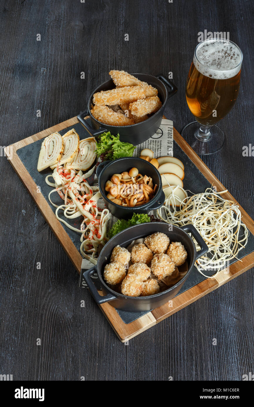 Große Auswahl an Snacks für Bier mit verschiedenen Soßen auf Pergament, Ansicht von oben Stockfoto