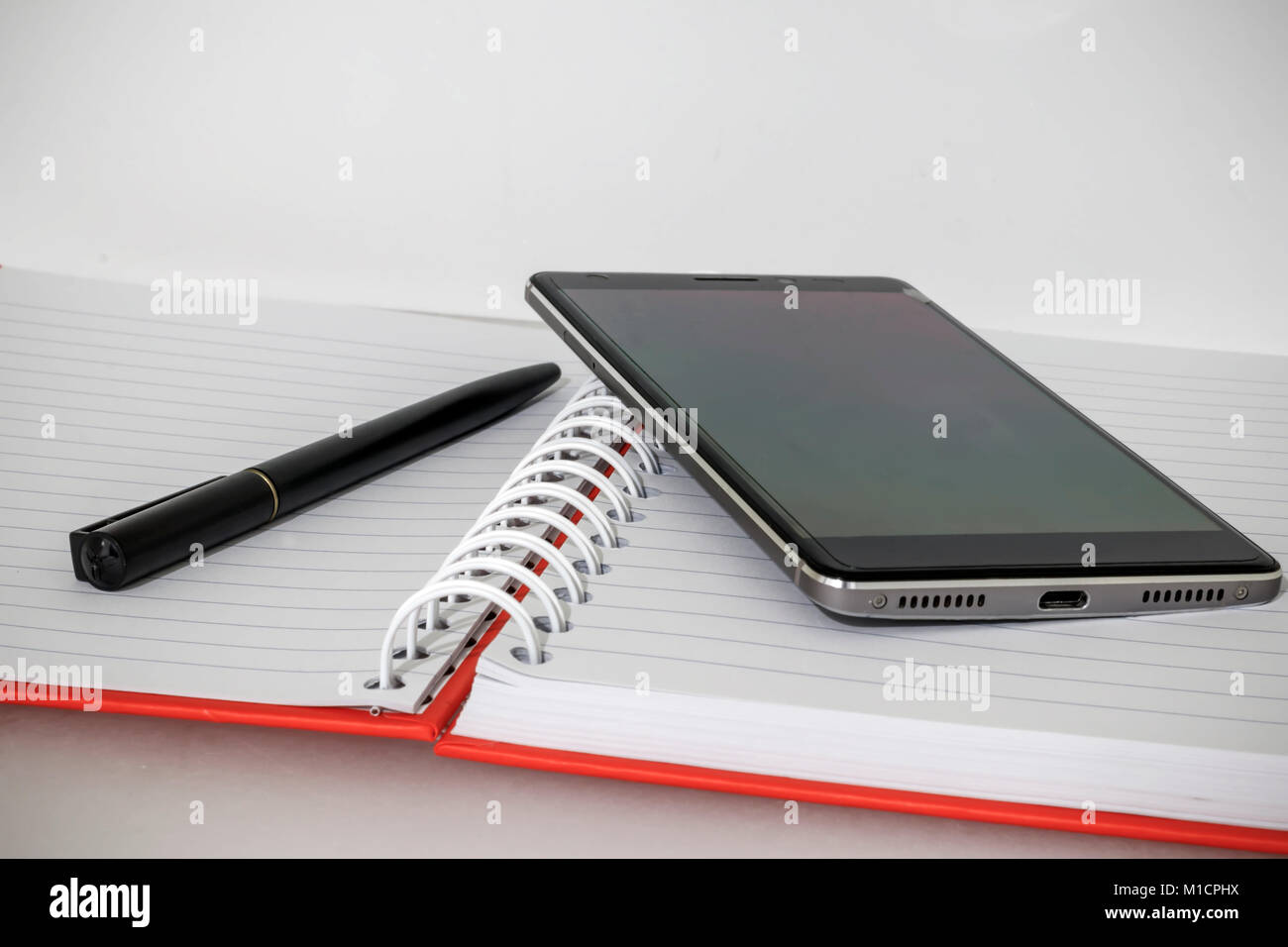 Notebook mit Stift und Handy geöffnet ist Stockfoto