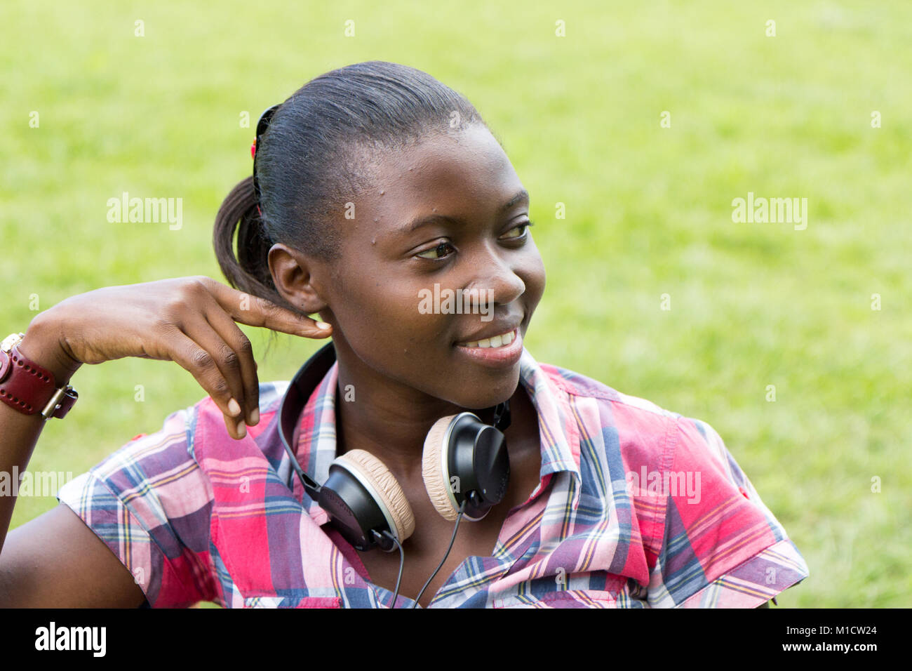 Einen schönen lächelnden Jungen ugandische Frau mit Kopfhörer um den Hals Stockfoto